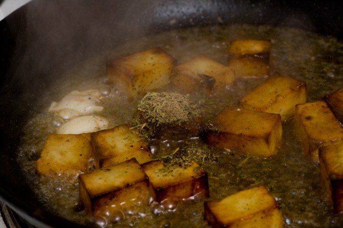 Hønse fond, knust timian, peber og et knust hvidløg tilsættes kartoflerne