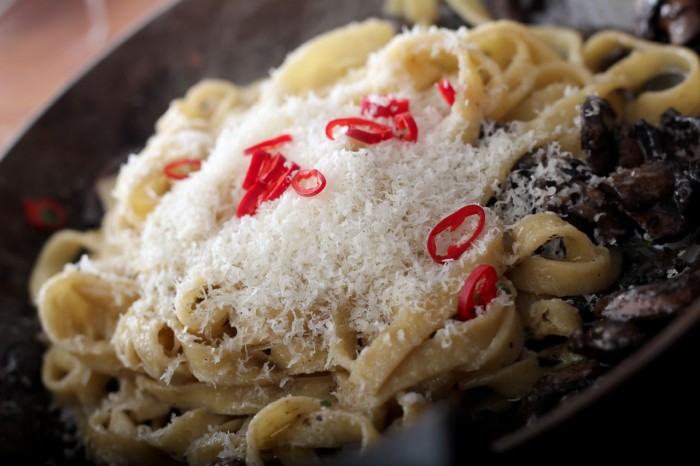 Læg den kogte pasta på panden og riv parmesan over. Tilsæt lidt hakket chili