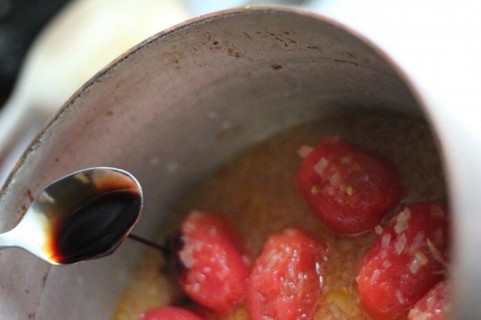 Hæld de flåede tomater og vand i gryden. Tilsæt en lille spiseskefuld balasamisk eddike