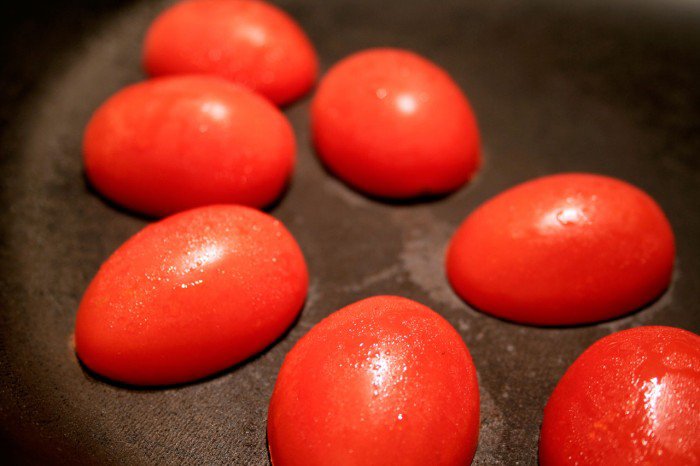 De halve tomater ligges med snitfladen ned af på en rigtig varm pande