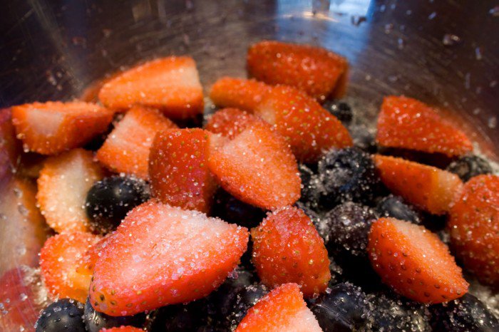 Halverede jordbær og blåbær med sukker