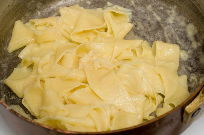Hjemmelavet pasta efter den er kommet tilbage i gryden med smør, fint revet hvidløg og Parmigiano-Reggiano