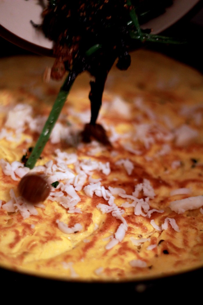 Svampe, bønner og revet manchego ligges oven på omeletten